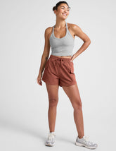 model wearing a gray tank top and auburn shorts on a plain background.